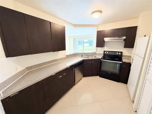a kitchen with granite countertop a sink a stove and refrigerator