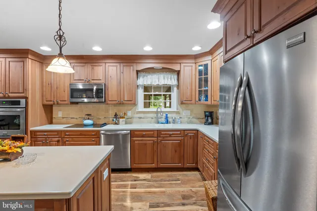 a kitchen with stainless steel appliances granite countertop a sink a stove a refrigerator and island with wooden floor