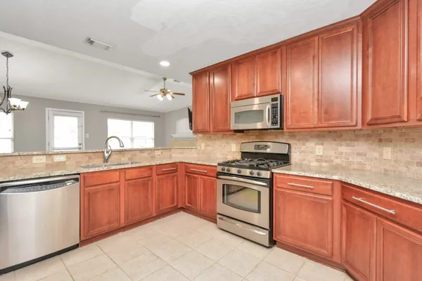 a kitchen with stainless steel appliances granite countertop wooden cabinets sink and a granite counter top