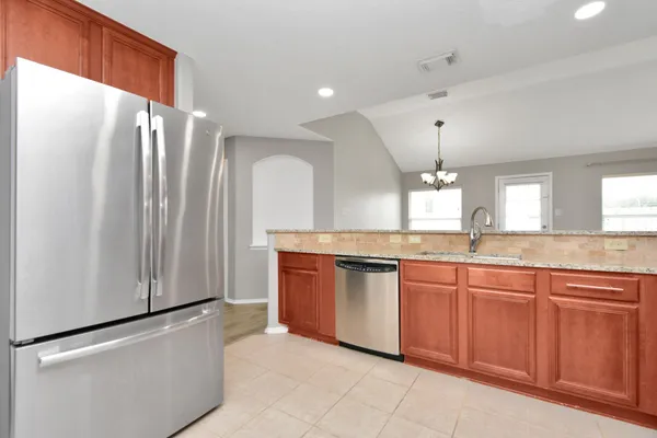 a large kitchen with stainless steel appliances granite countertop a refrigerator and a sink