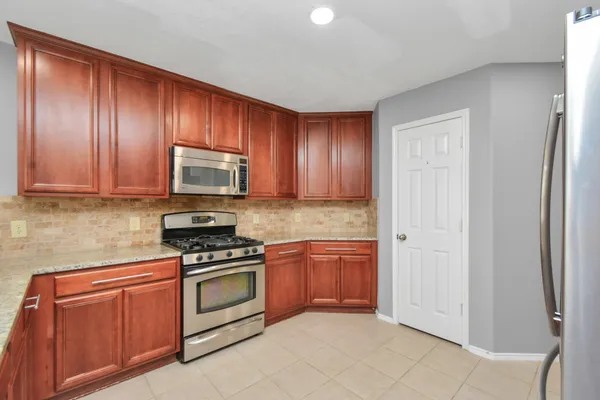 a kitchen with granite countertop stainless steel appliances a stove top oven and cabinets