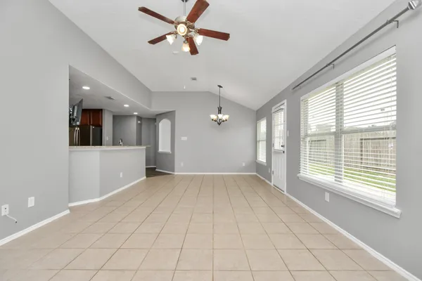 a view of an empty room with a window and a kitchen
