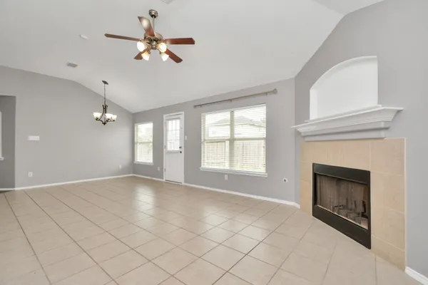 a view of an empty room with chandelier fan and fire place