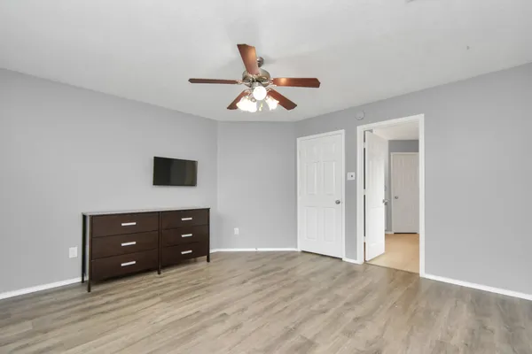 a room with a dresser and a ceiling fan