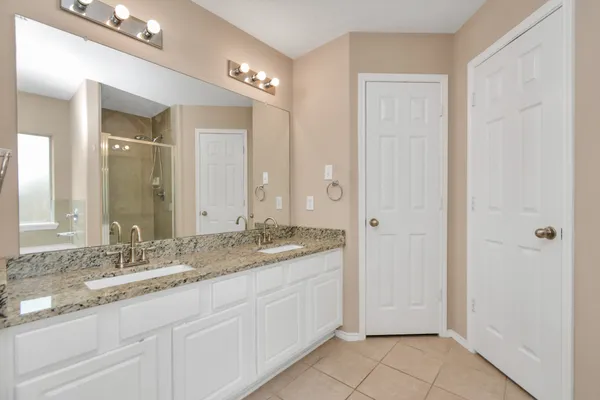 a bathroom with a granite countertop double vanity sink a mirror and a