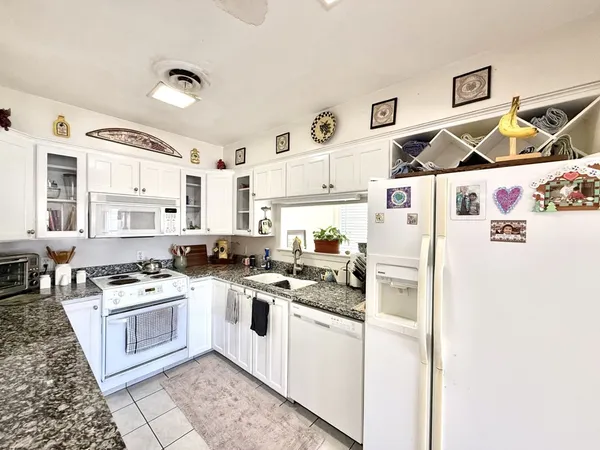 a white kitchen with stainless steel appliances granite countertop a stove and a refrigerator
