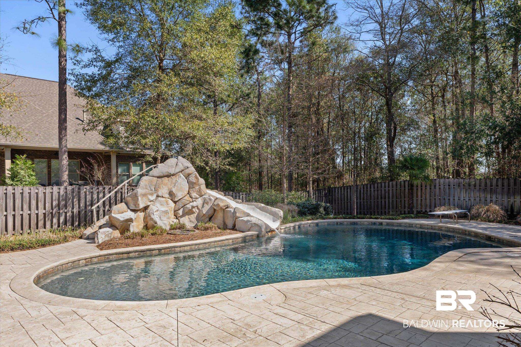 7676 Rockstone Lane Mobile, AL 36695 - Photo 34 of 47 View of swimming pool featuring a fenced backyard, patio surround, a water slide, and a diving board