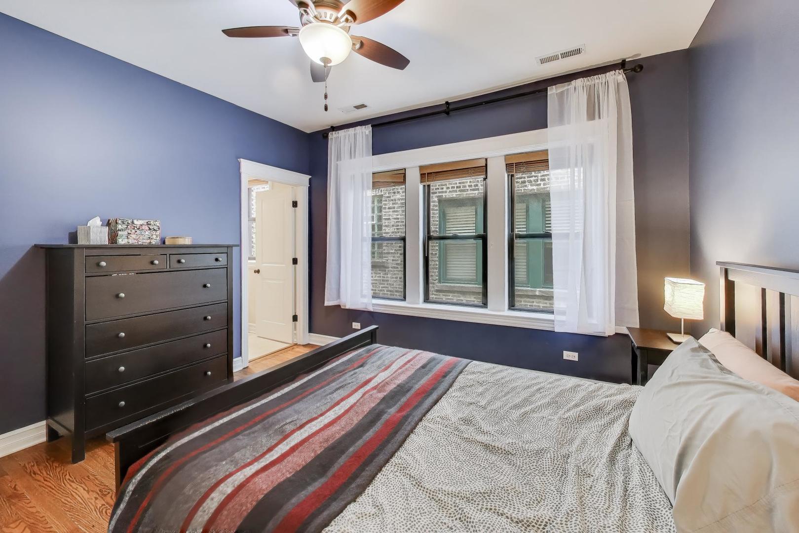 4441 North Beacon Street, Unit 2A Chicago, IL 60640 - Photo 12 of 23 a bedroom with a bed and a chandelier