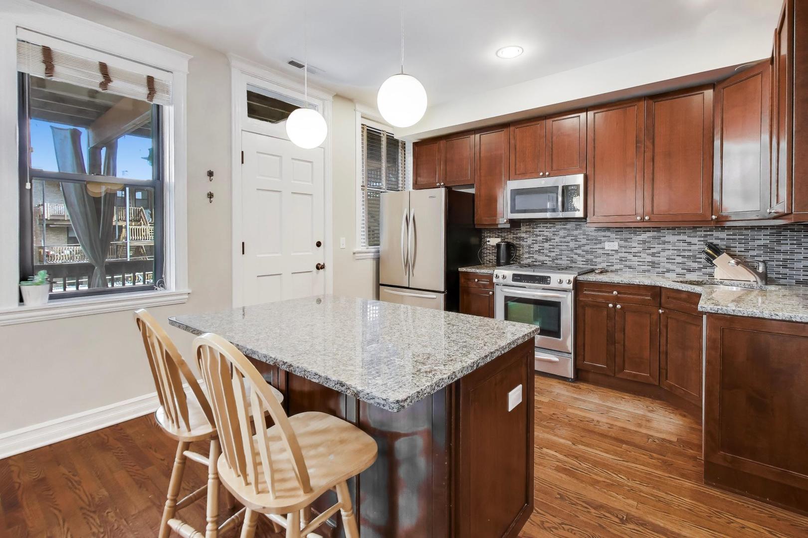 4441 North Beacon Street, Unit 2A Chicago, IL 60640 - Photo 10 of 23 a kitchen with stainless steel appliances granite countertop a kitchen island hardwood floor sink stove and refrigerator