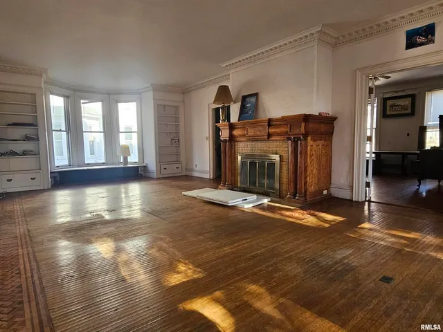 a view of a room that has a bed and wooden floor