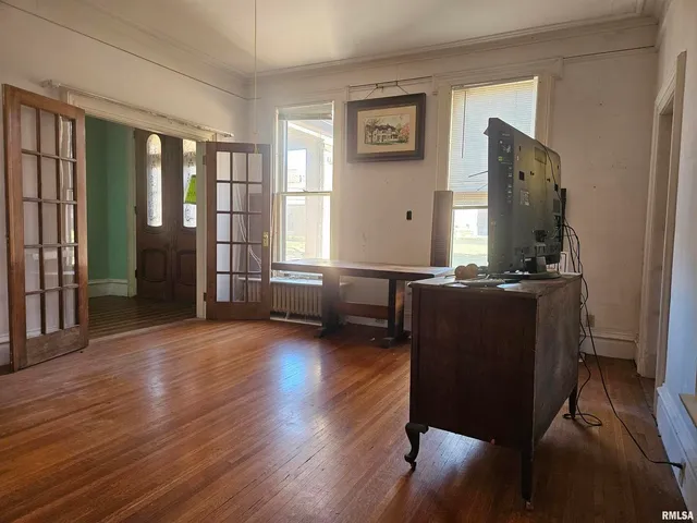 a view of an empty room with a window and wooden floor