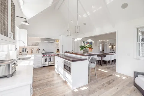 a kitchen with white cabinets and wooden floor