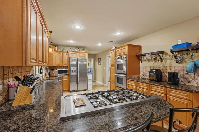 a kitchen with stainless steel appliances granite countertop a stove a sink and a microwave
