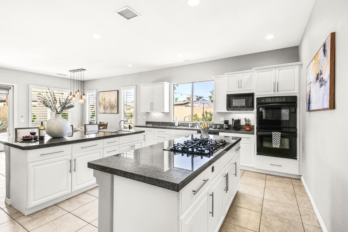 48713 Spring Rain Court Indio, CA 92201 - Photo 24 of 66 a kitchen with stainless steel appliances kitchen island granite countertop a sink and cabinets