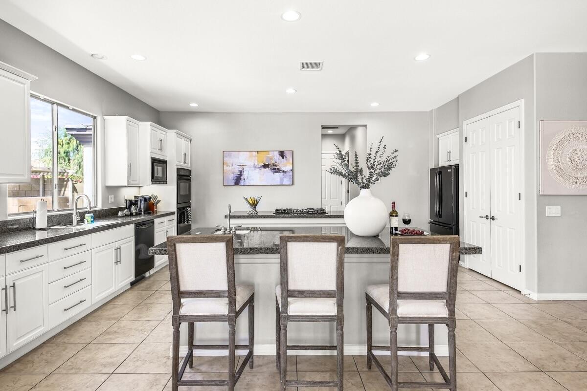 48713 Spring Rain Court Indio, CA 92201 - Photo 25 of 66 a kitchen with stainless steel appliances kitchen island granite countertop a table and chairs in it