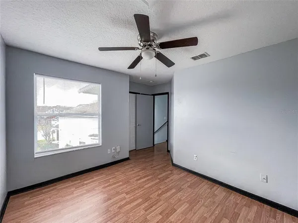 a view of empty room with wooden floor and fan