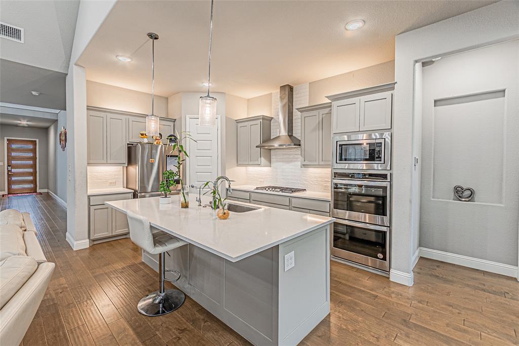 13261 Jonata Street Frisco, TX 75035 - Photo 13 of 40 a kitchen with stainless steel appliances a stove a sink dishwasher a refrigerator and white cabinets with wooden floor