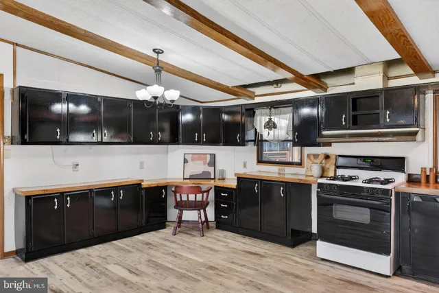 an empty room with chandelier fan and windows
