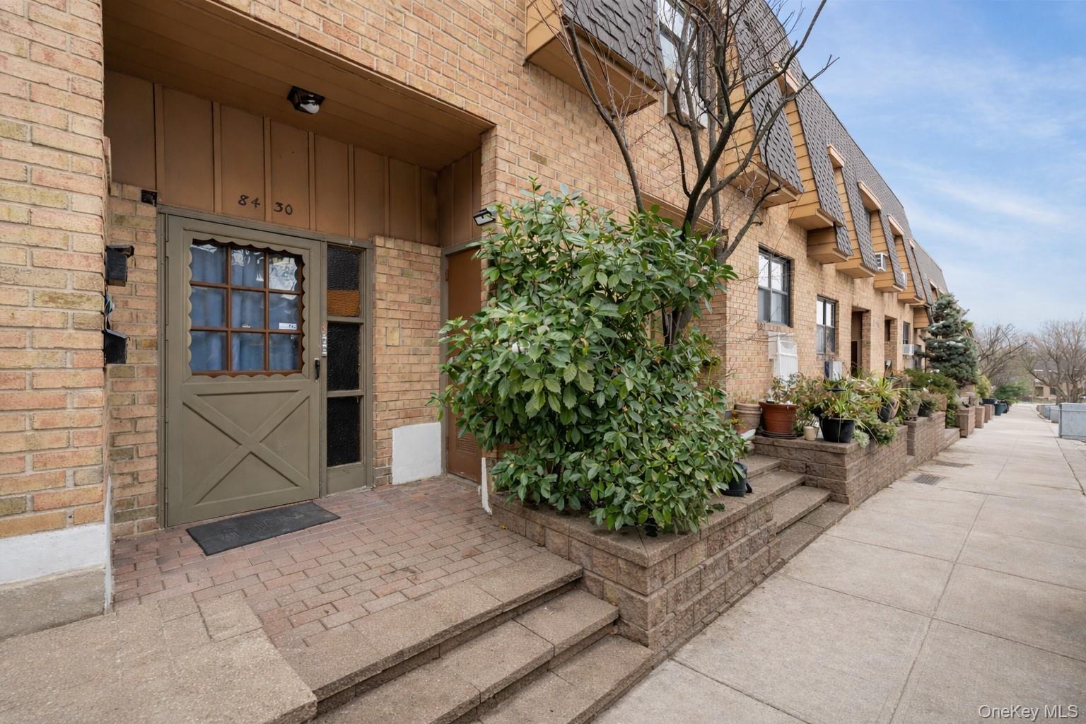 84-30 98th Street Queens, NY 11421 - Photo 2 of 35 View of exterior entry featuring brick siding and board and batten siding