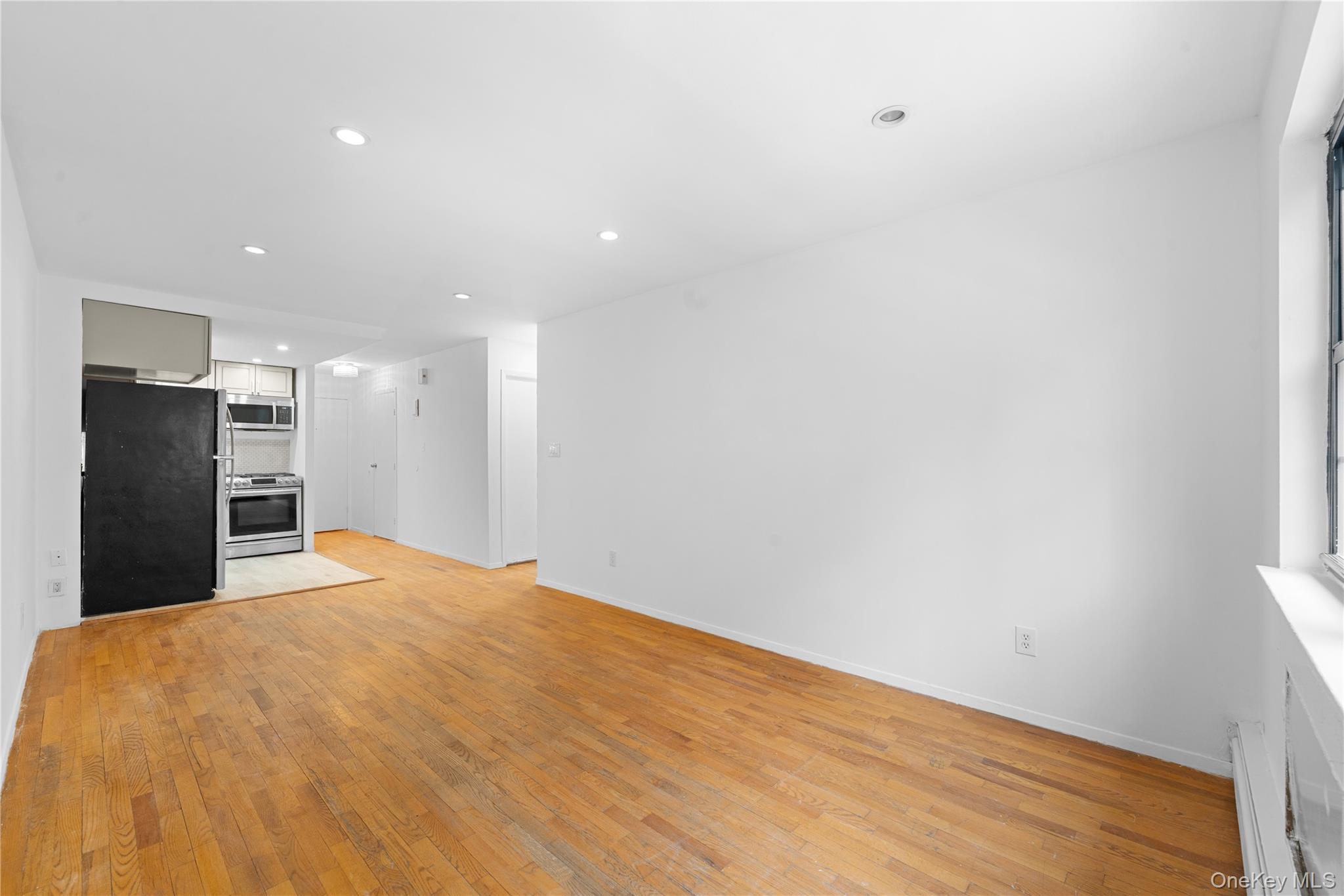 84-30 98th Street Queens, NY 11421 - Photo 22 of 35 Unfurnished living room featuring recessed lighting, light wood finished floors, and a baseboard heating unit
