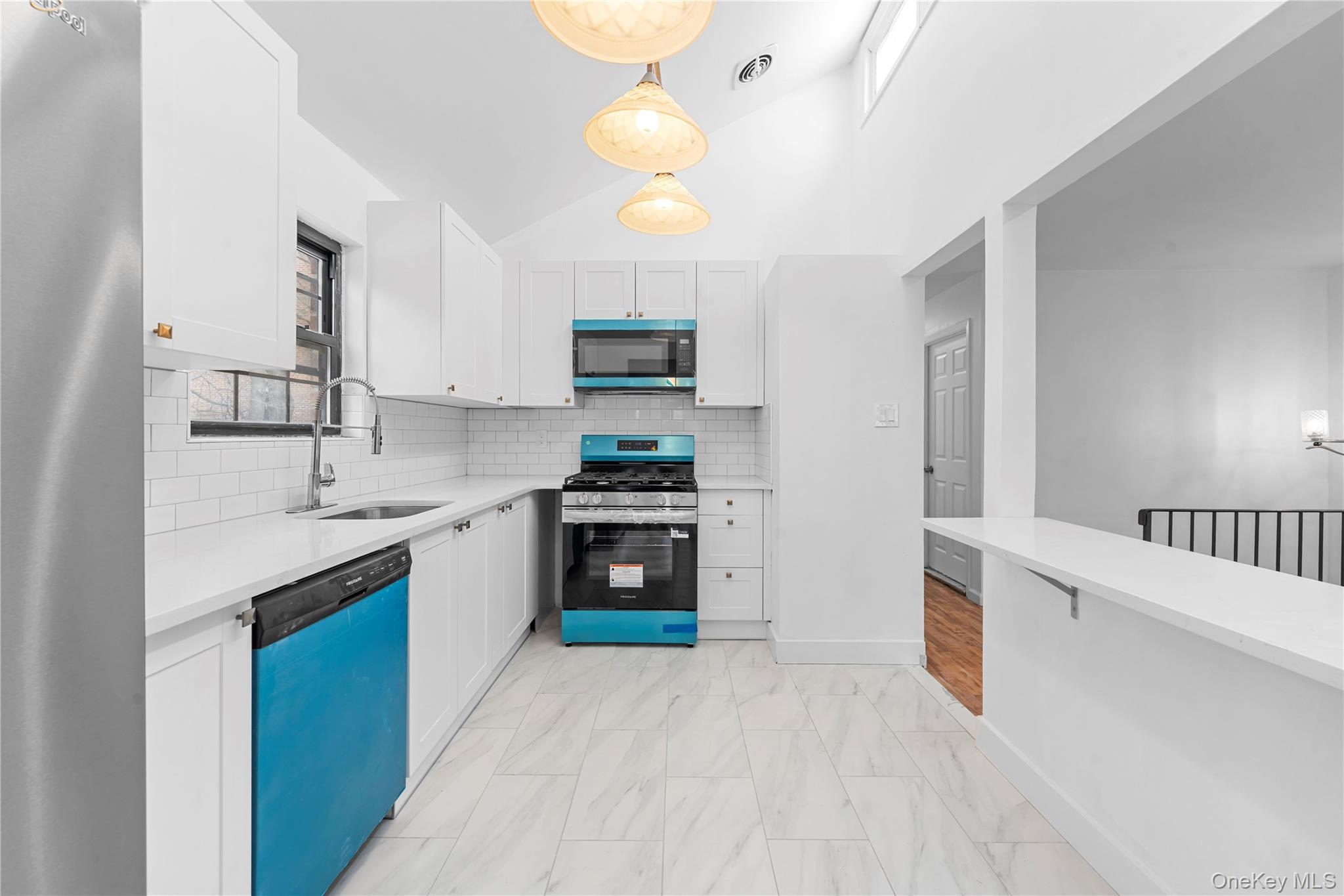 84-30 98th Street Queens, NY 11421 - Photo 4 of 35 Kitchen with appliances with stainless steel finishes, white cabinets, decorative light fixtures, light stone countertops, and decorative backsplash