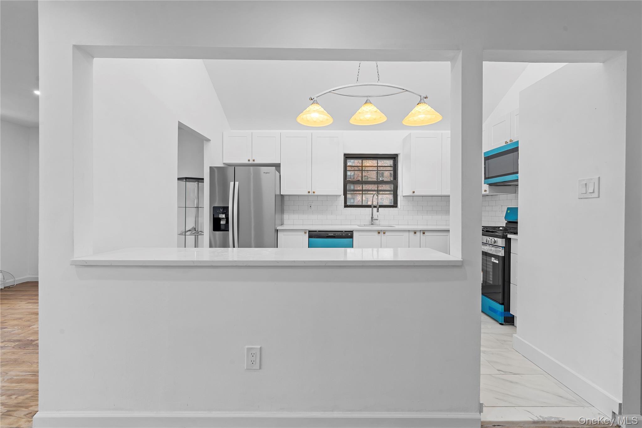 84-30 98th Street Queens, NY 11421 - Photo 5 of 35 Kitchen featuring white cabinets, appliances with stainless steel finishes, hanging light fixtures, light stone counters, and decorative backsplash