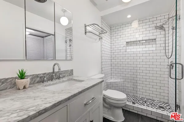 a bathroom with a granite countertop sink a toilet and shower