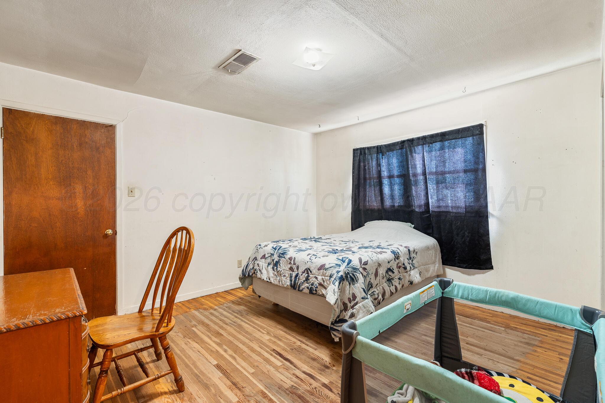 1790 Farm To Market Road 145 Hart, TX 79043 - Photo 16 of 28 a bedroom with a bed and wooden floor