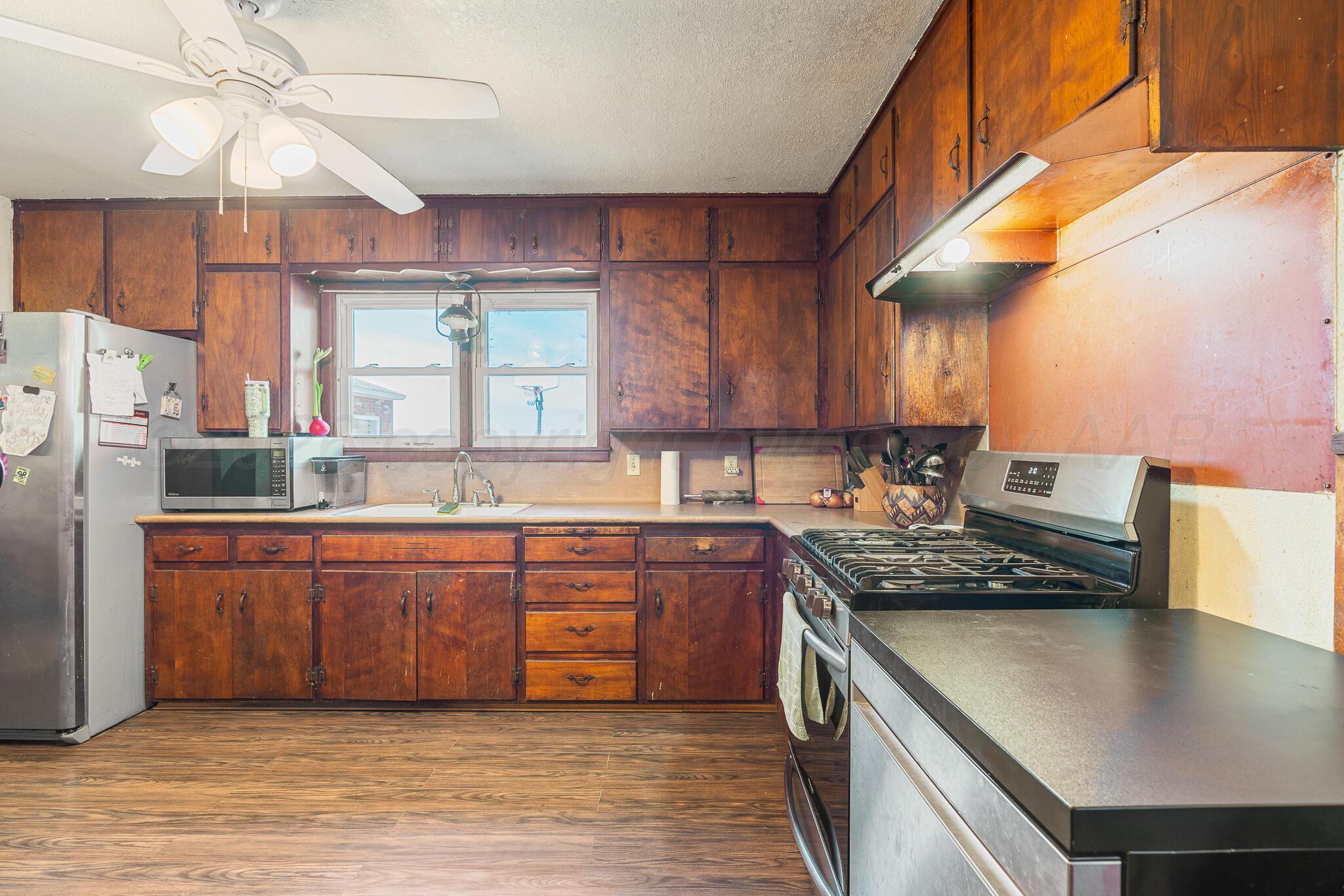 1790 Farm To Market Road 145 Hart, TX 79043 - Photo 19 of 28 a kitchen with stainless steel appliances granite countertop a sink a stove and a wooden floors
