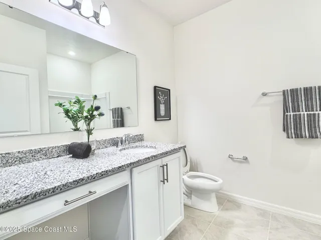 a bathroom with a granite countertop sink a toilet and a mirror