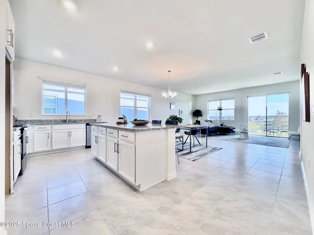 a kitchen with stainless steel appliances granite countertop a stove top oven a sink a dining table and chairs