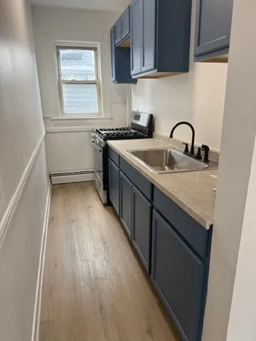 a kitchen with a sink a stove cabinets and a wooden floor