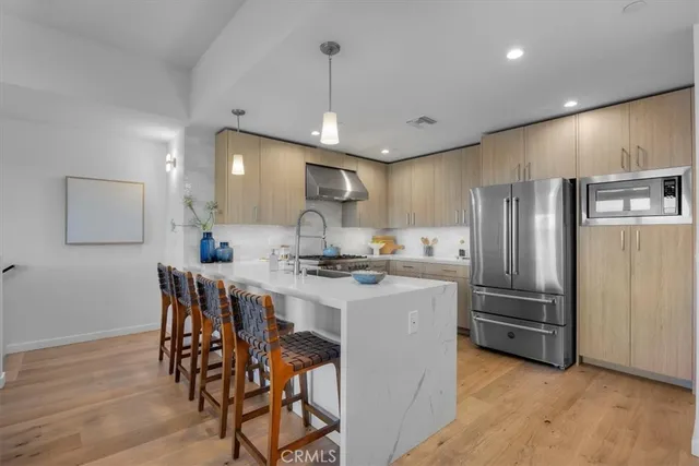 a kitchen with stainless steel appliances a table chairs refrigerator and microwave
