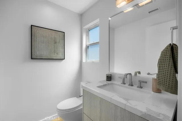 a bathroom with a granite countertop sink mirror vanity and toilet