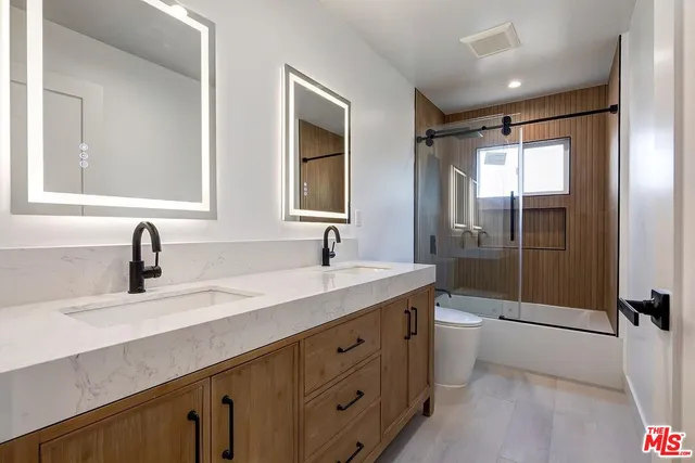 a bathroom with a double vanity sink toilet mirror and bathtub