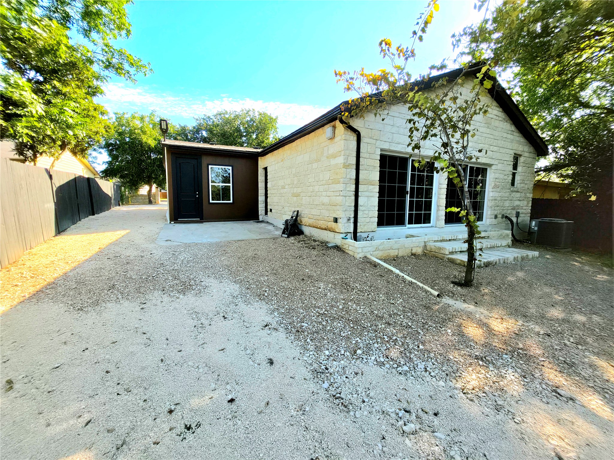 2201 Teri Road Austin, TX 78744 - Photo 32 of 40 Natural stone masonry and a wide gravel driveway define this versatile back exterior space.