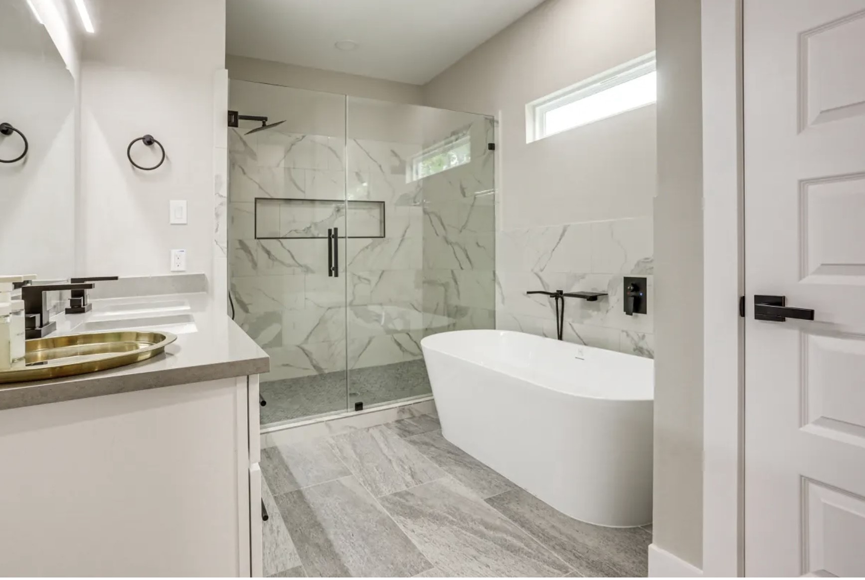 3727 Dreyfus Street Houston, TX 77021 - Photo 12 of 17 This modern bathroom features a sleek freestanding tub, a spacious glass-enclosed shower with marble-style tiles, and a contemporary vanity with a stylish sink. Natural light enhances its bright, elegant design.