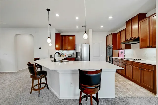 a large kitchen with stainless steel appliances granite countertop a refrigerator a sink dishwasher a oven with white cabinets and wooden floor