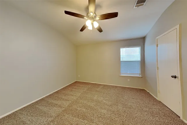 an empty room with a chandelier fan and windows