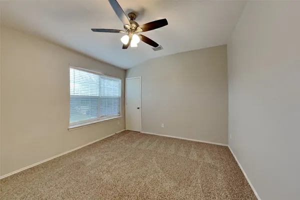 an empty room with a chandelier fan and windows
