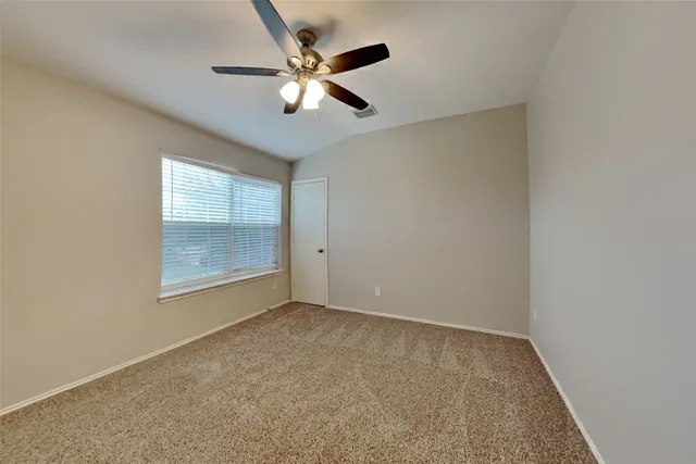 an empty room with a chandelier fan and windows