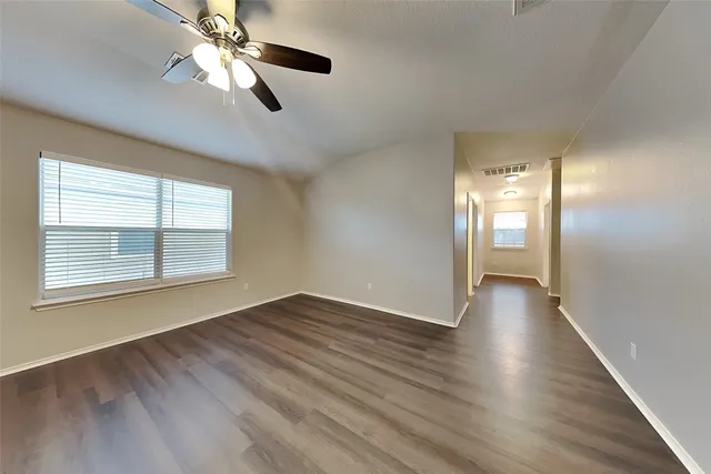 a view of an empty room with wooden floor and a window