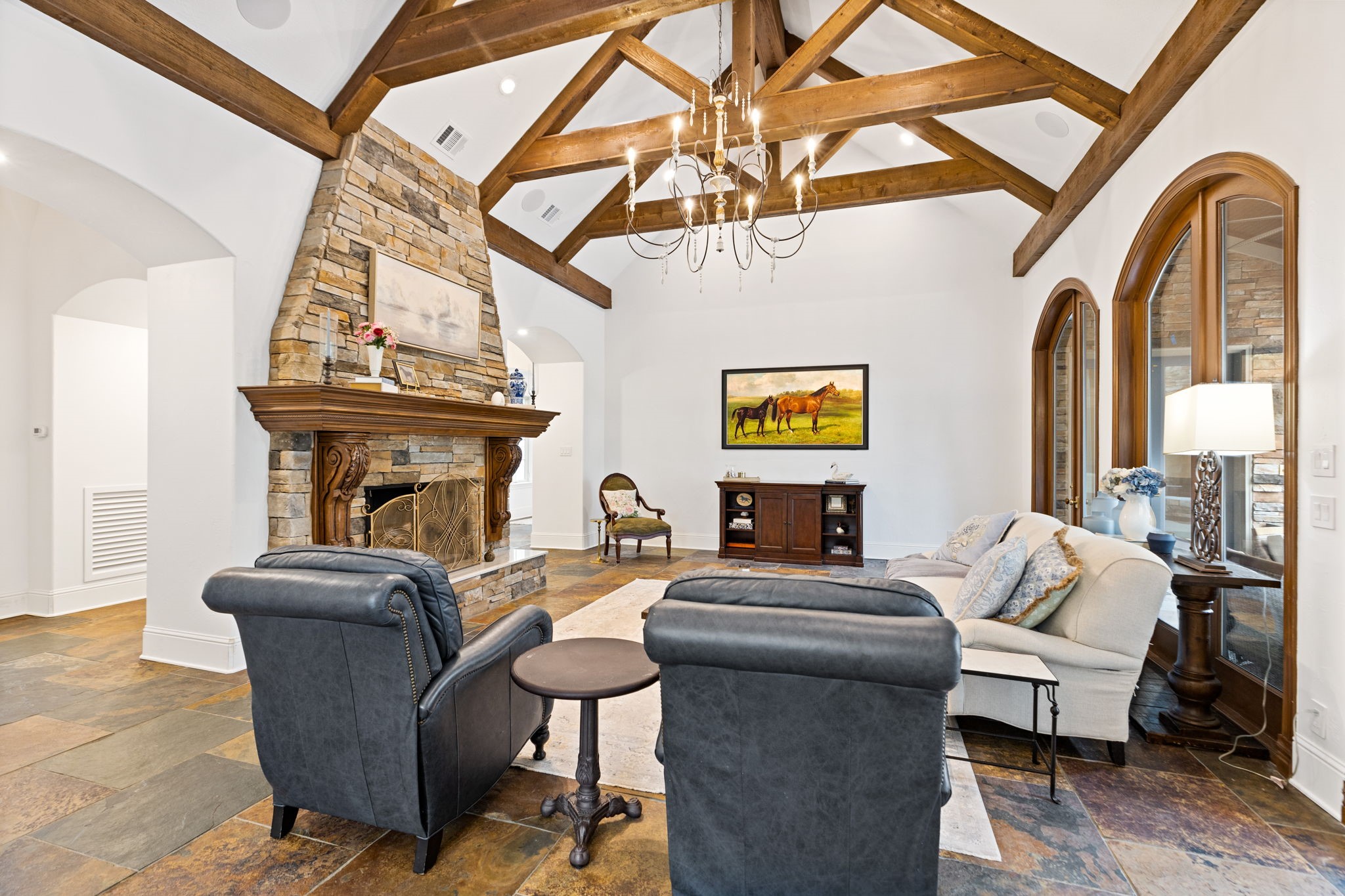 38223 Windy Ridge Trail Magnolia, TX 77355 - Photo 11 of 48 This fabulous family room features a high vaulted ceiling with exposed wooden beams, a stone fireplace, and elegant arch windows that overlook the pool. Gorgeous chandelier adds a touch of sophistication.