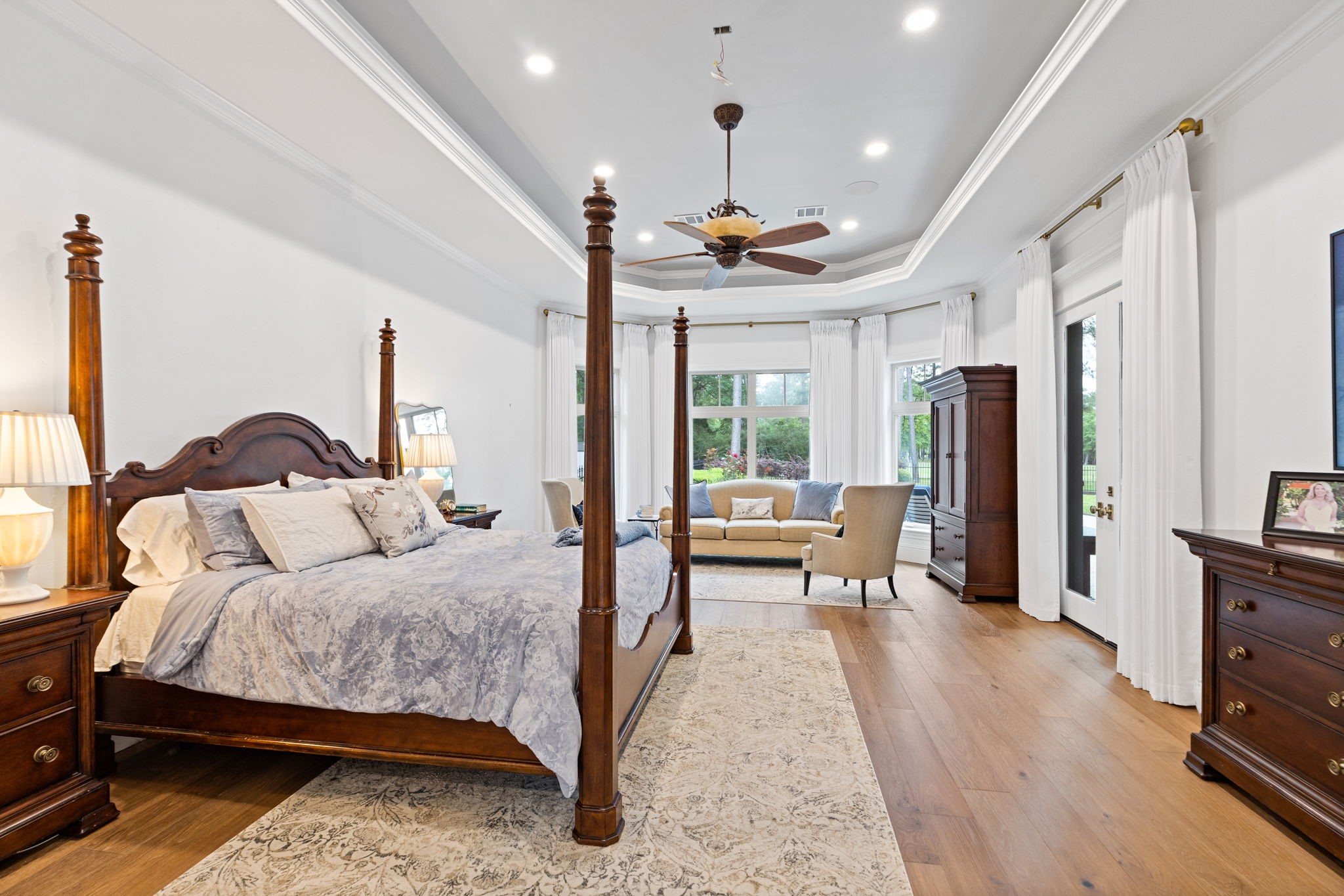 38223 Windy Ridge Trail Magnolia, TX 77355 - Photo 20 of 48 This spacious primary bedroom features elegant tray ceilings, and ample natural light from expansive windows. It includes a cozy sitting area, engineered hardwood floors, double doors that lead to the covered patio this primary bedroom offers both comfort and sophistication.