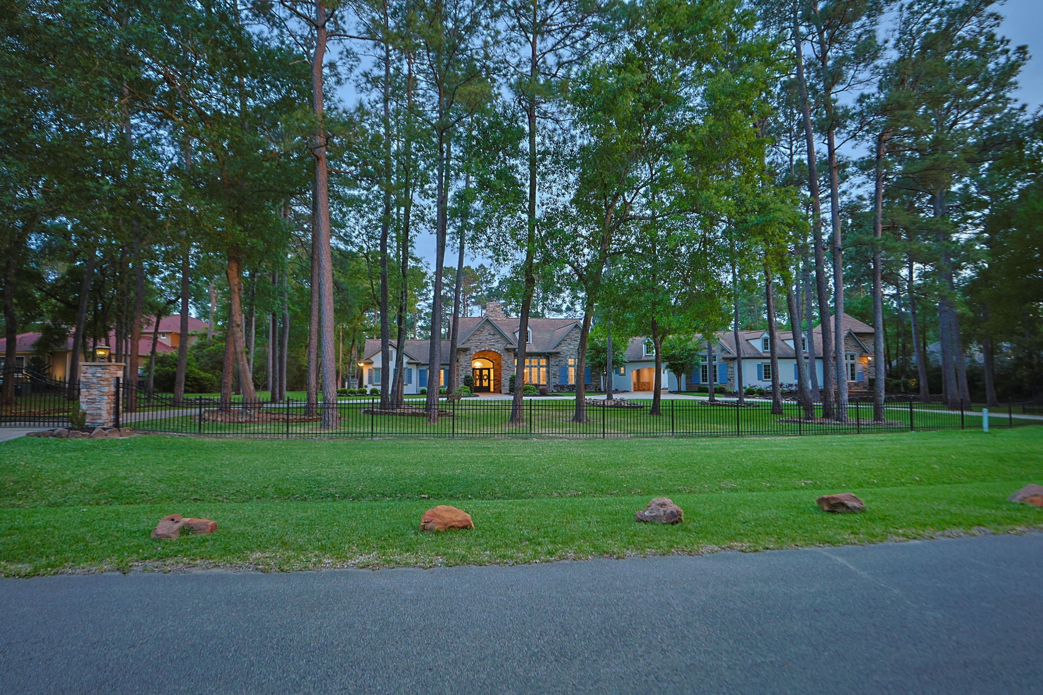 38223 Windy Ridge Trail Magnolia, TX 77355 - Photo 2 of 48 This sunset photo shows a spacious, elegant home set amidst tall trees, offering a serene and private atmosphere. The property features a gated entry with a circular driveway for convenience. Ideal for those seeking tranquility and privacy.