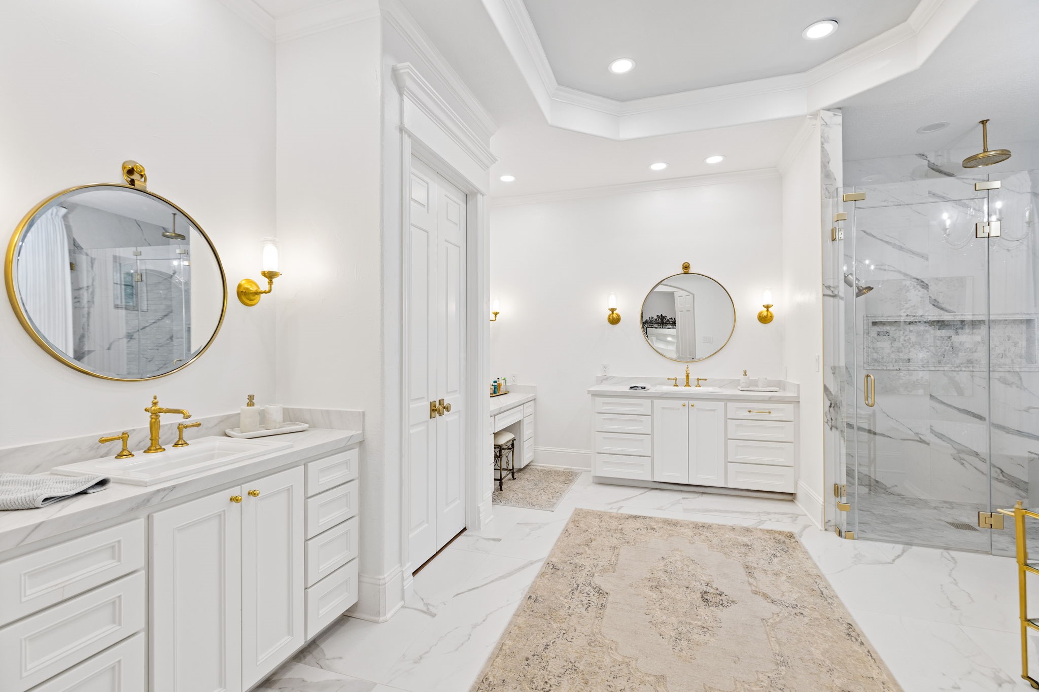 38223 Windy Ridge Trail Magnolia, TX 77355 - Photo 22 of 48 This remodeled primary bathroom features a luxurious design with dual vanities, elegant gold fixtures, and round mirrors. It has a spacious glass-enclosed shower with marble accents, white cabinetry, Quartz countertops, marble flooring, huge walk in closet, creating a bright and sophisticated spa like atmosphere.