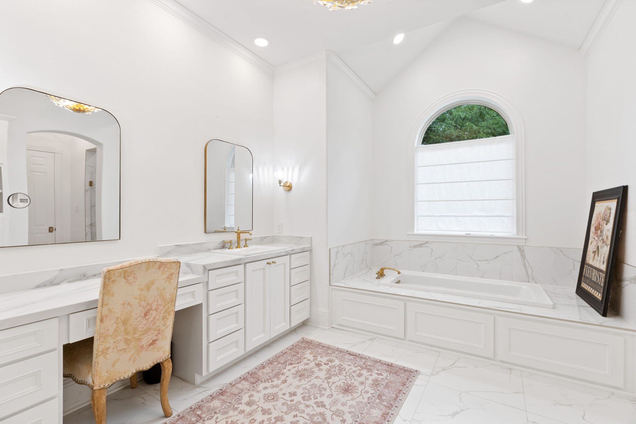 38223 Windy Ridge Trail Magnolia, TX 77355 - Photo 31 of 48 This bathroom (could be another primary bath) features a luxurious design with white cabinetry, Quartz countertops, and a spacious built-in tub. It includes a large arched window for natural light, elegant gold fixtures, a classic vanity area , a shower, and a large walk in closet.