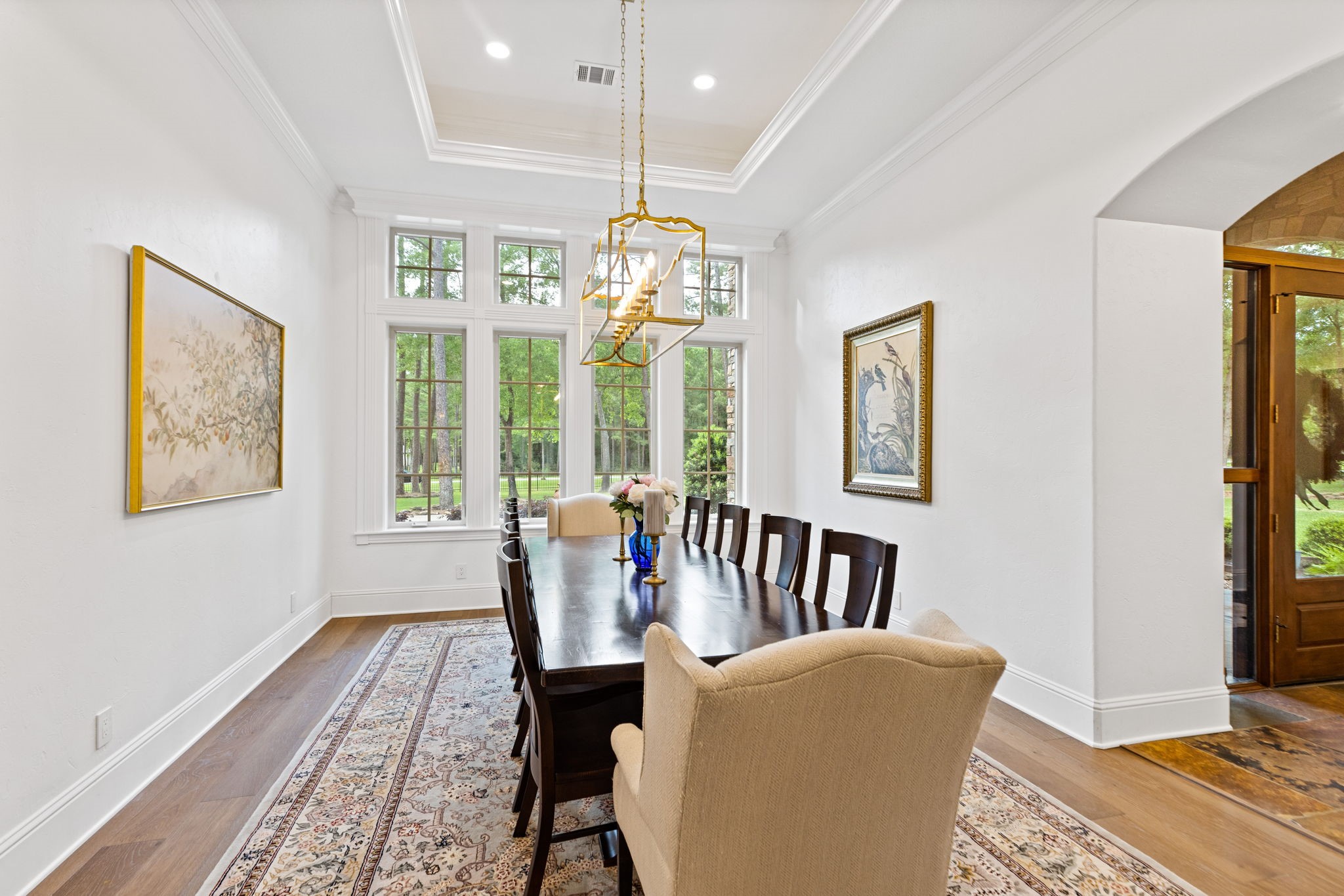 38223 Windy Ridge Trail Magnolia, TX 77355 - Photo 9 of 48 This photo showcases a spacious, elegant dining room with room for your large tables. It features high ceilings, a modern chandelier, and large windows offering plenty of natural light with a view of the front yard. This dining room is complete with stunning engineered wood floors, crown molding, recessed lighting, and a tray ceiling.