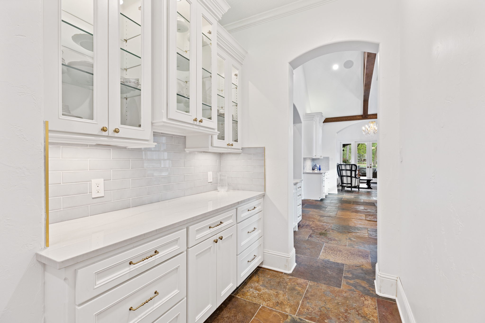 38223 Windy Ridge Trail Magnolia, TX 77355 - Photo 10 of 48 This photo showcases a bright butler's pantry with gorgeous sleek white cabinetry and glass-front upper cabinets that provide plenty of storage for your dishes. The slate tile flooring enhances the elegant, open feel.