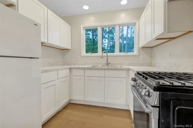 a kitchen with granite countertop a sink a window stainless steel appliances and cabinets